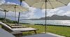 Seaside loungers shaded by umbrellas on a grassy terrace overlooking the Caribbean Sea at a St Barts villa rental.