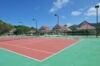 Outdoor tennis court surrounded by tropical hills and villas, part of luxury vacation rentals in St Barts.