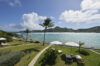 Expansive beachfront lawn with sun loungers and swaying palms overlooking turquoise waters at a St Barts luxury villa.