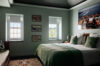 Elegant bedroom with green bedding, framed artwork and natural light in St Barts villa rental