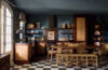 Rustic villa kitchen with wicker cabinetry, wooden dining table, and checkered floor in St Barts vacation rental