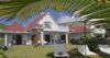 Charming white villa with red roof, garden loungers, and tropical palms in a beachfront St Barts vacation rental.