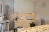 Compact modern kitchen with patterned tile countertops, built-in oven, and bright white cabinetry in a St Barts villa rental.