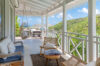 Shaded veranda at St Barts villa with lounge chairs, swing seat, and hillside views