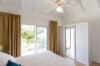 Simple bedroom with sliding glass doors, ceiling fan, and terrace access at St Barts villa rental