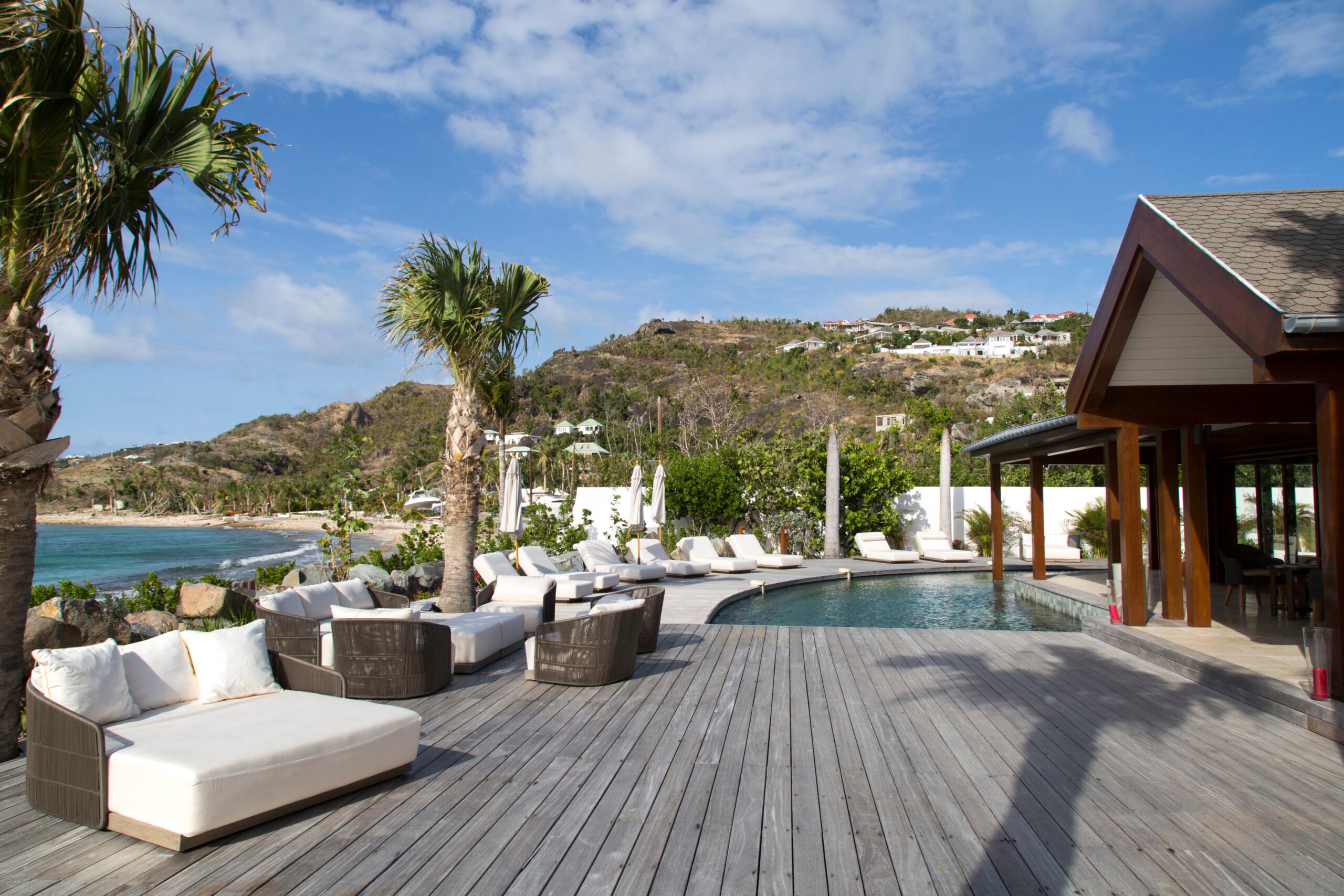 Spacious pool deck with lounge chairs, ocean views, and hillside backdrop at a luxury villa in St Barts