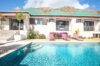 Private villa pool with clear blue water, pink loungers, and tropical garden in St Barts luxury rental