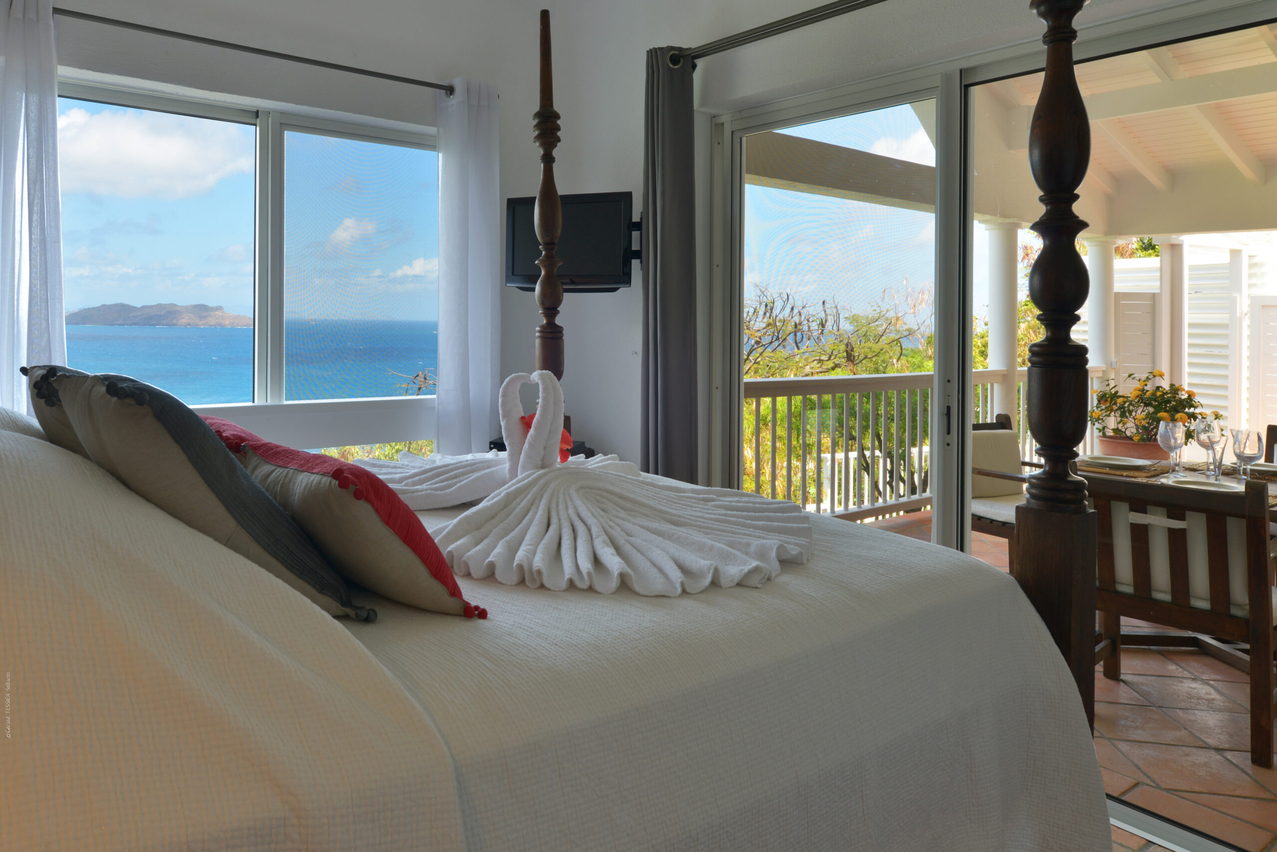 Romantic bedroom at a St Barts villa with swan towel décor and panoramic ocean views.