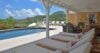 Covered terrace with cushioned sun loungers overlooking pool and hillside views in a St Barts villa rental