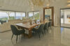 Elegant villa dining room with wooden table, modern chairs, and ocean view terrace in St Barts luxury vacation rental.