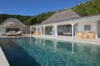 Elegant villa with shaded terrace, wicker lounge chairs, and long turquoise pool in St Barts luxury villa rental.