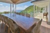 Spacious villa terrace with long wooden dining table, wicker chairs, and ocean views in St Barts luxury vacation rental.