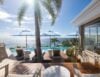 Poolside terrace with sun loungers and blue umbrellas overlooking the Caribbean Sea at a luxury villa in St Barts.