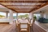 Shaded outdoor dining area with wooden table and hillside views connecting to open living spaces in a St Barts villa rental.
