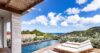 Poolside loungers overlooking lush hills and Caribbean Sea under bright blue skies at a St Barts villa rental.