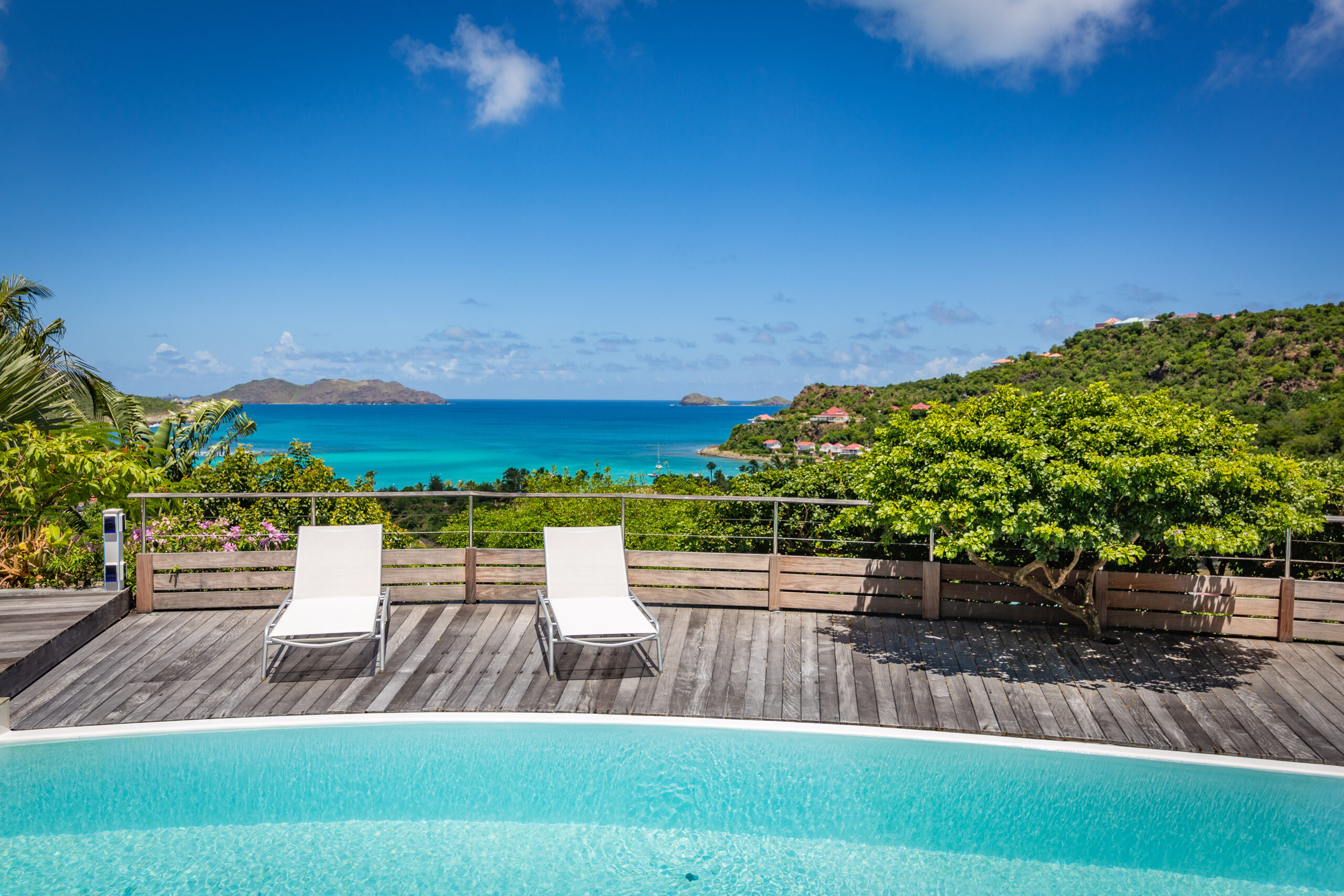 Curved infinity pool at a St Barts villa rental with sun loungers and turquoise sea views.