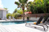Private villa rental in St Barts with sun loungers around a wooden deck pool shaded by palm trees