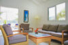 Bright living room with rattan furniture and glass coffee table opening to terrace at St Barts villa rental