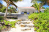 Beachfront villa in St Barts with stone steps leading from sandy shore to shaded terrace