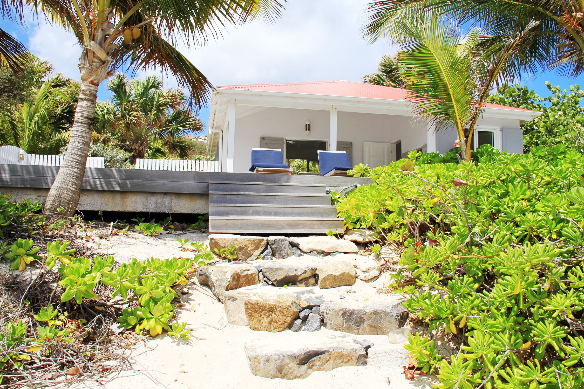 Beachfront villa in St Barts with stone steps leading from sandy shore to shaded terrace