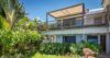 Modern two-story villa in St Barts with shaded balcony and lush tropical garden.