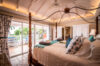 Elegant villa bedroom with four-poster bed, vaulted ceiling, and terrace access in St Barts