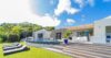 Contemporary St Barts villa with curved infinity pool, sun loungers on the lawn, and open-air living spaces.