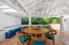 Covered garden dining area with round wooden table, blue seating, and tropical greenery in a St Barts villa rental.