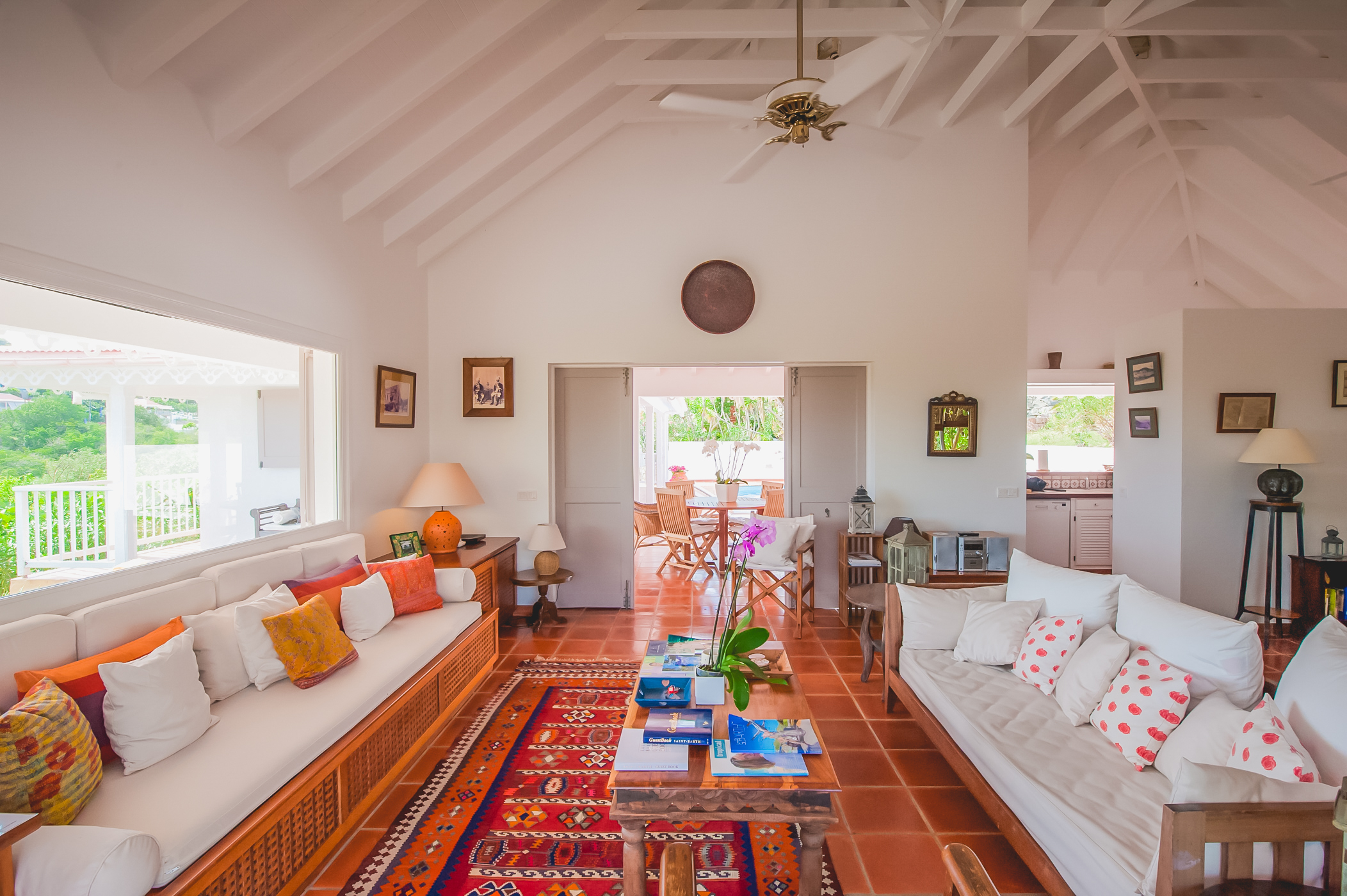 Colorful villa living room with white sofas, vibrant cushions, and terracotta tile floors in St Barts vacation rental.