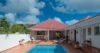 Charming villa courtyard with red roof, private pool, sun loungers, and shaded bar area in St Barts vacation rental.