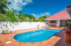 Sunny villa courtyard with terracotta tiles, private pool, sun loungers, and bar area in St Barts villa rental.