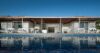Modern beachfront villa with shaded terrace, lounge chairs, and infinity pool reflecting the blue sky in St Barts