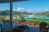 Covered terrace dining table overlooking pool loungers and turquoise bay views at a hillside St Barts villa rental.