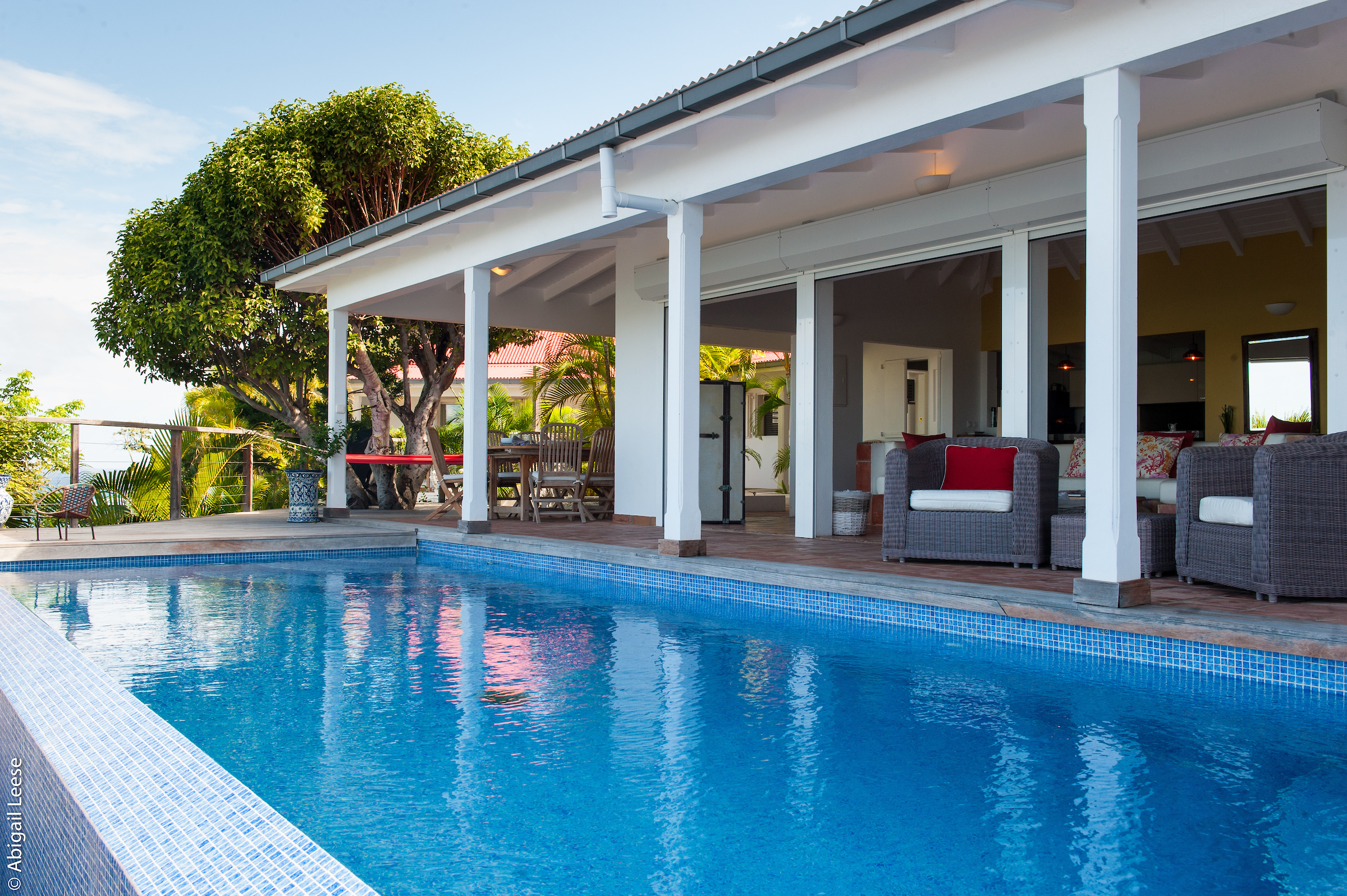 Shaded terrace with rattan seating overlooking a turquoise pool at a private luxury villa rental in St Barts.