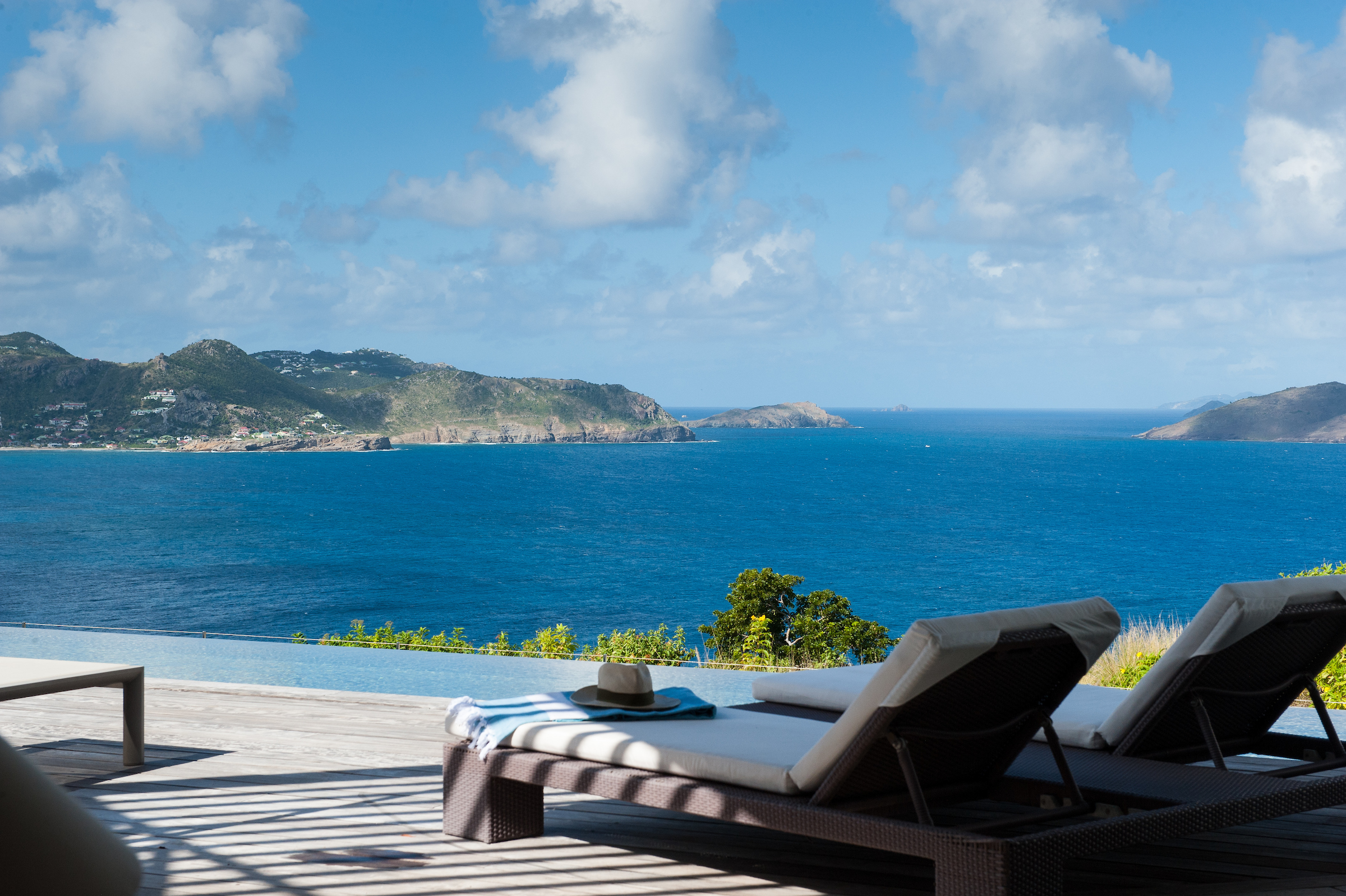 Elegant loungers arranged on a wooden deck, overlooking the turquoise Caribbean Sea.