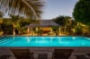 Evening view of illuminated swimming pool surrounded by palm trees at a luxury villa in St Barts