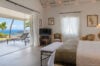 “Bedroom with terrace access, lounge chairs, and ocean view at St Barts villa rental
