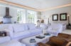 Bright living space in St Barts villa with white sofas, modern kitchen, and cozy reading corners.