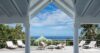 Open-air terrace of a St Barts villa with ocean views, sun loungers, and tropical palms under blue skies.