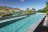 Long infinity pool with sun loungers, tropical garden, and ocean views at St Barts luxury villa