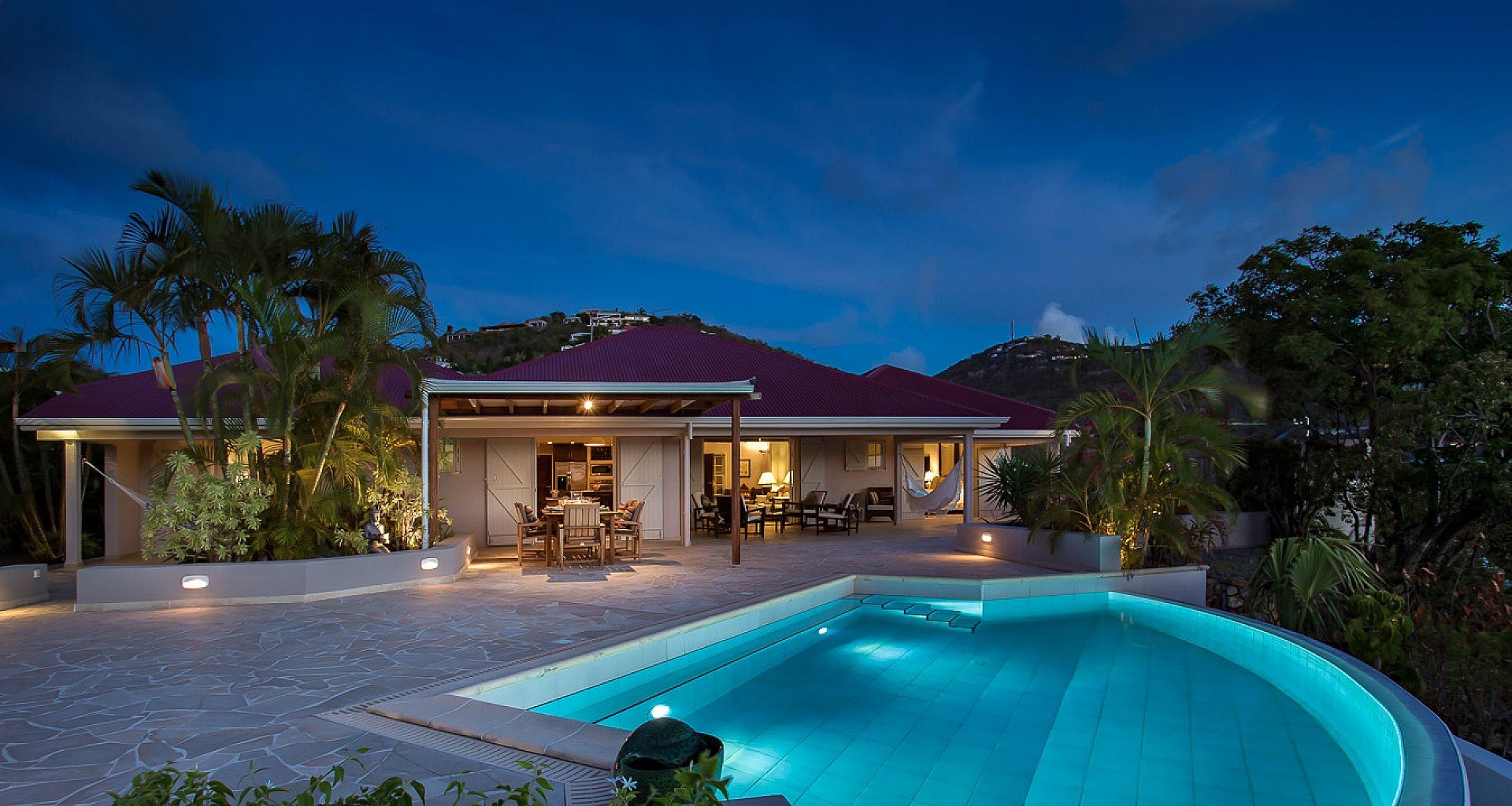 Luxury St Barts villa pool illuminated at night with ocean view and ambient lighting