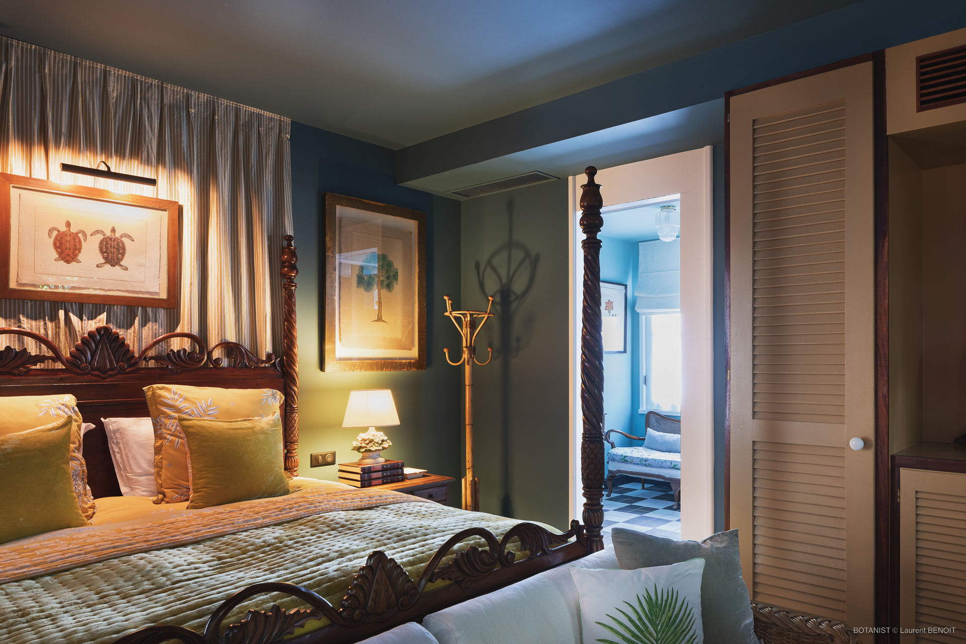 Elegant villa bedroom with carved wooden bedframe, framed artwork, and warm lighting in St Barts vacation rental