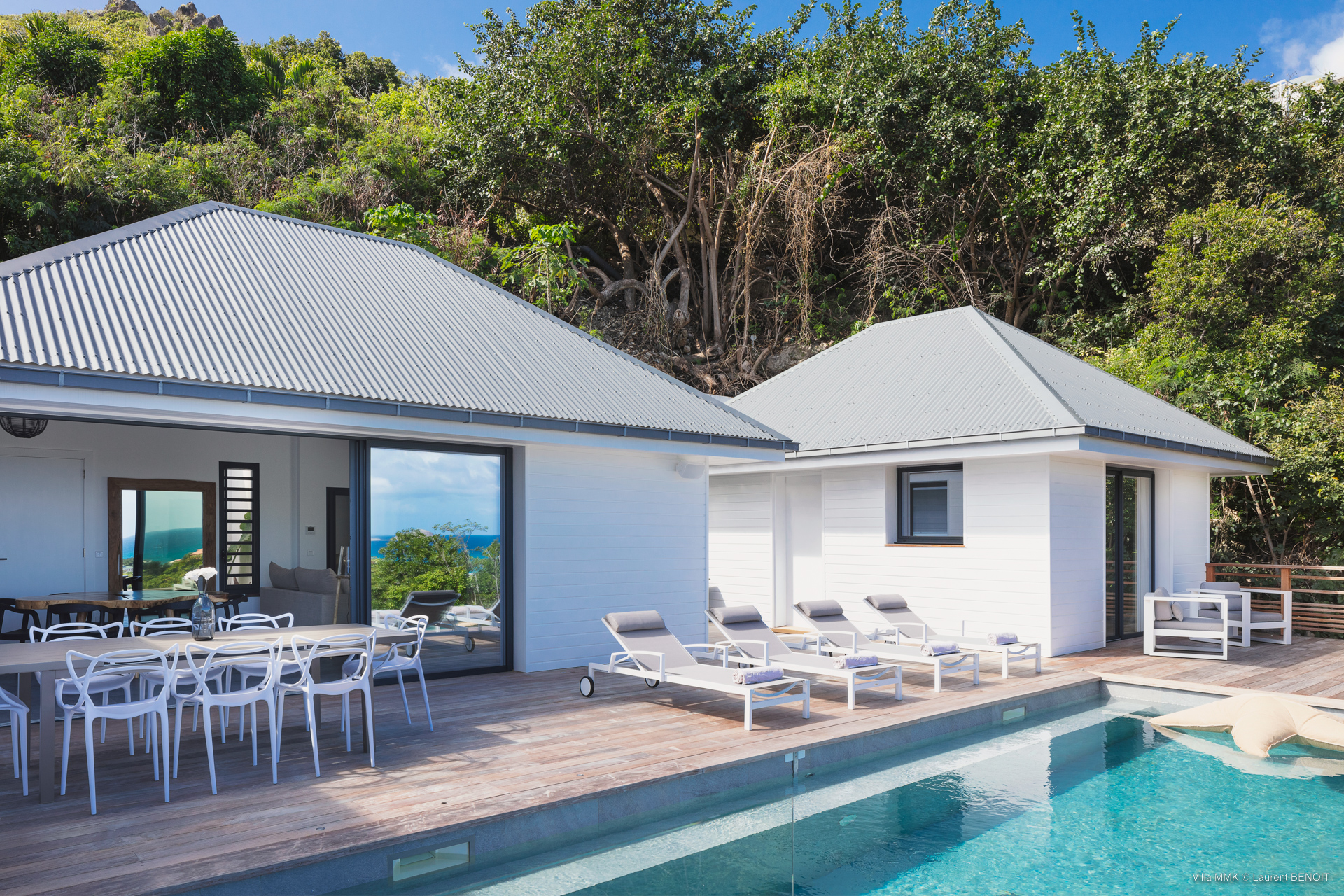 Poolside deck with sun loungers and outdoor dining area beside a contemporary St Barts villa rental.