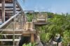 Elevated wooden terrace of a St Barts villa with glass railing, lounge seating and tropical garden views