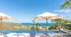 Infinity pool at a St Barts villa with white sunbeds, umbrellas, and sweeping views of the Caribbean Sea and green hills.