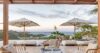 Terrace lounge at a St Barts villa with rattan chairs, sun umbrellas, and panoramic ocean views at sunset.