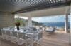 Covered outdoor dining terrace in a St Barts villa with elegant table setting, lounge chairs, and sweeping ocean views.