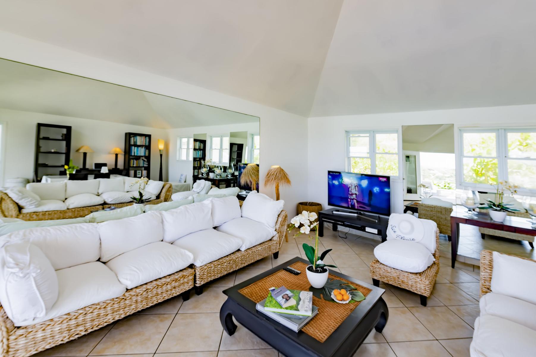Spacious villa living room with white sofas, wicker accents, and bright natural light in a St Barts vacation rental.