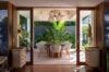 Elegant dining area in a St Barts villa with tropical greenery backdrop and modern woven chairs.