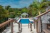 Private pool area of a St Barts villa surrounded by palm trees and tropical greenery with gazebo lounge